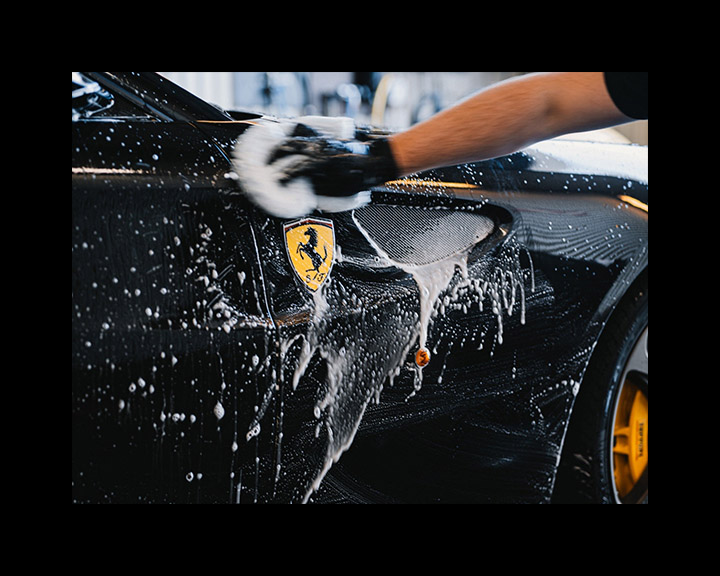 Foam-mitt hand wash on a black Ferrari